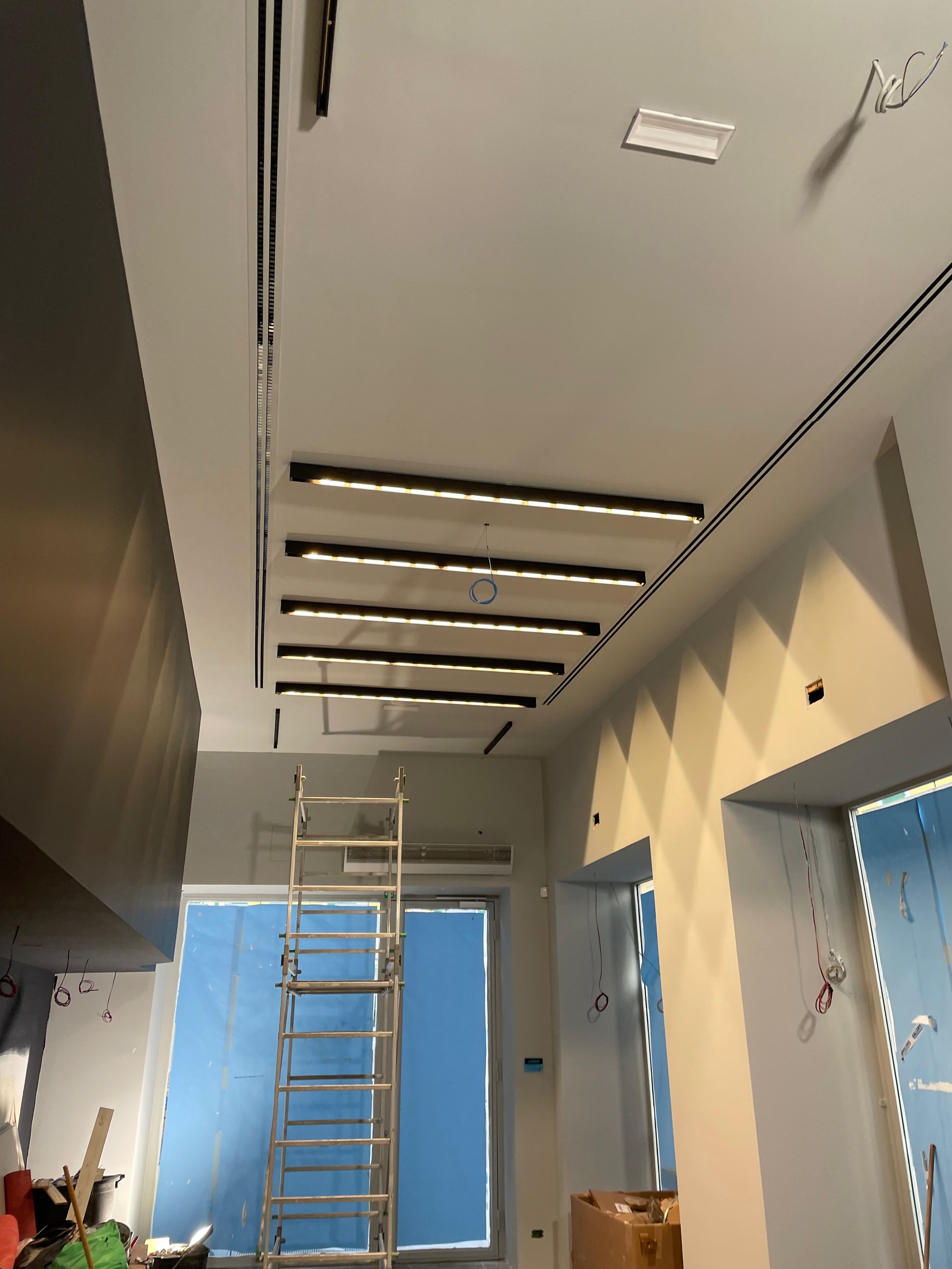 Soffitto di un negozio retail in fase di apertura, con binari LED sospesi appena installati per l'illuminazione principale